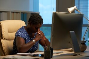 afro-american-woman-sitting-front-computer-office-leaning-head-clasped-hands-300x200 About us.