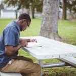 african american male sitting at a table and reading the bible