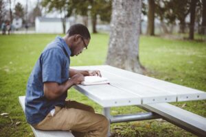 african american male sitting at a table and reading the bible
